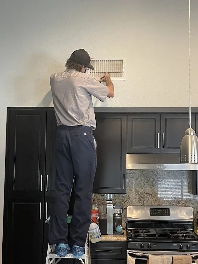 Technician inspecting an air vent during HVAC service in Eagle